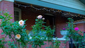 Un edificio de ladrillo con un porche decorado con luces colgantes y plantas en macetas.