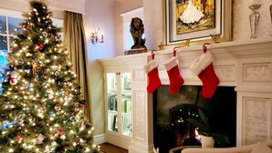 Un árbol de Navidad decorado, una chimenea con calcetines navideños y un cuadro en la pared.