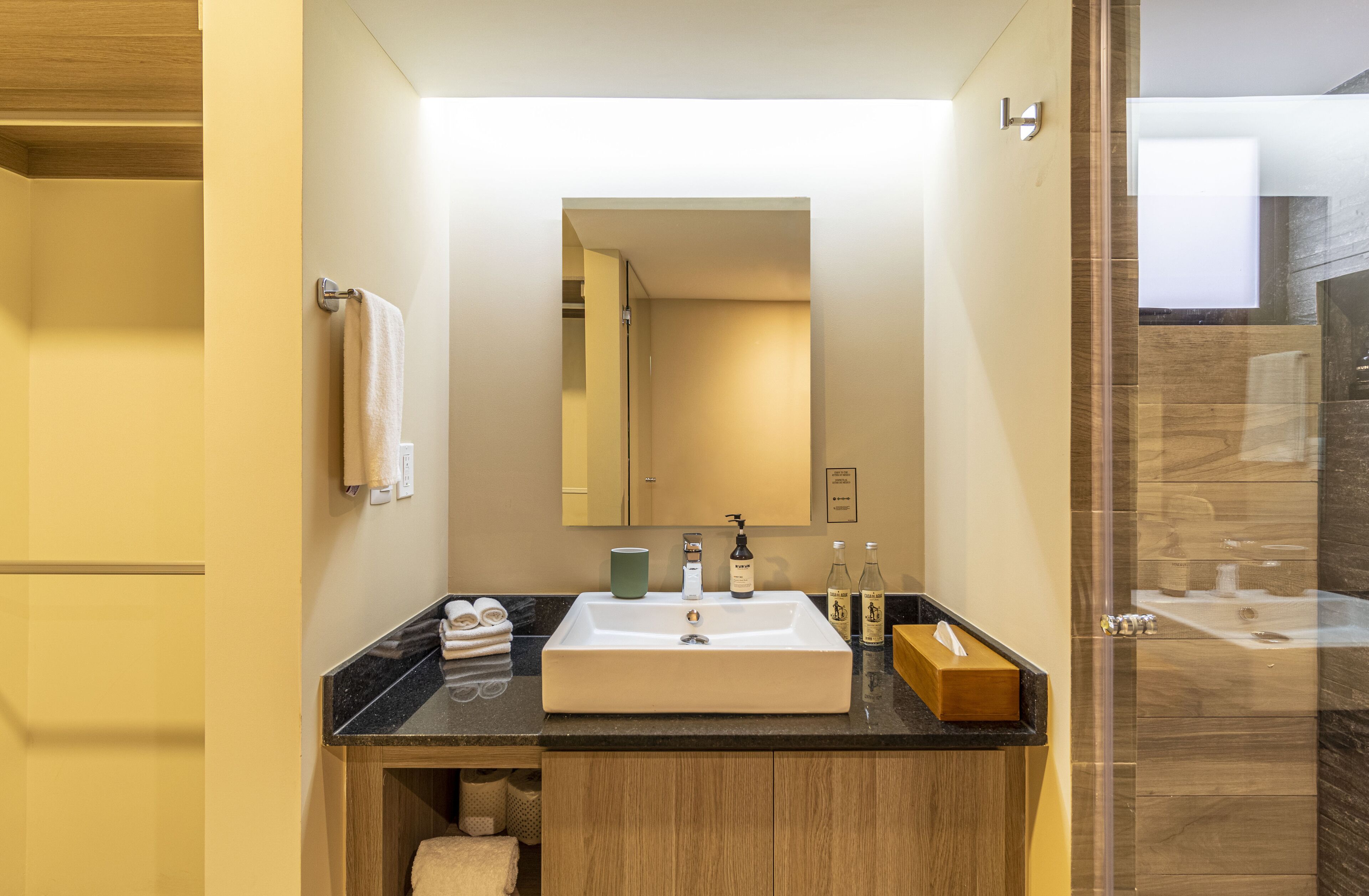 A modern bathroom with a large sink, mirror, and wooden vanity.
