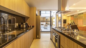 Eine moderne Küche mit Holzschränken, einer schwarzen Arbeitsplatte, Edelstahlgeräten und Blick zum Essbereich.