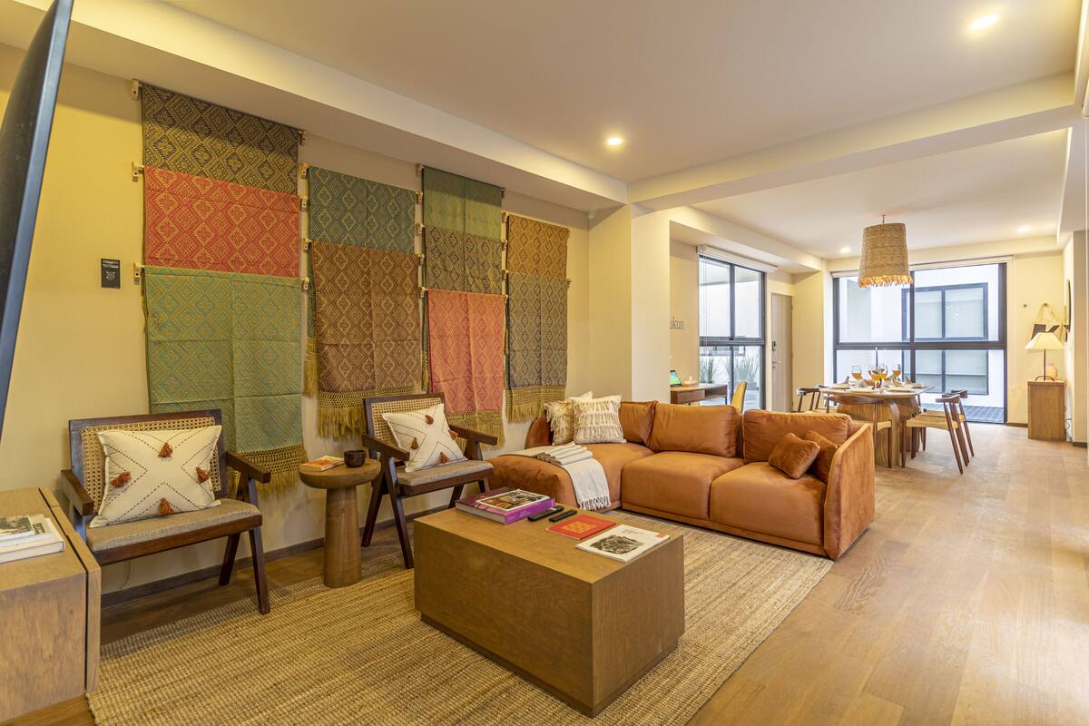 A modern living room with a sofa, chairs, a coffee table, and a dining area.