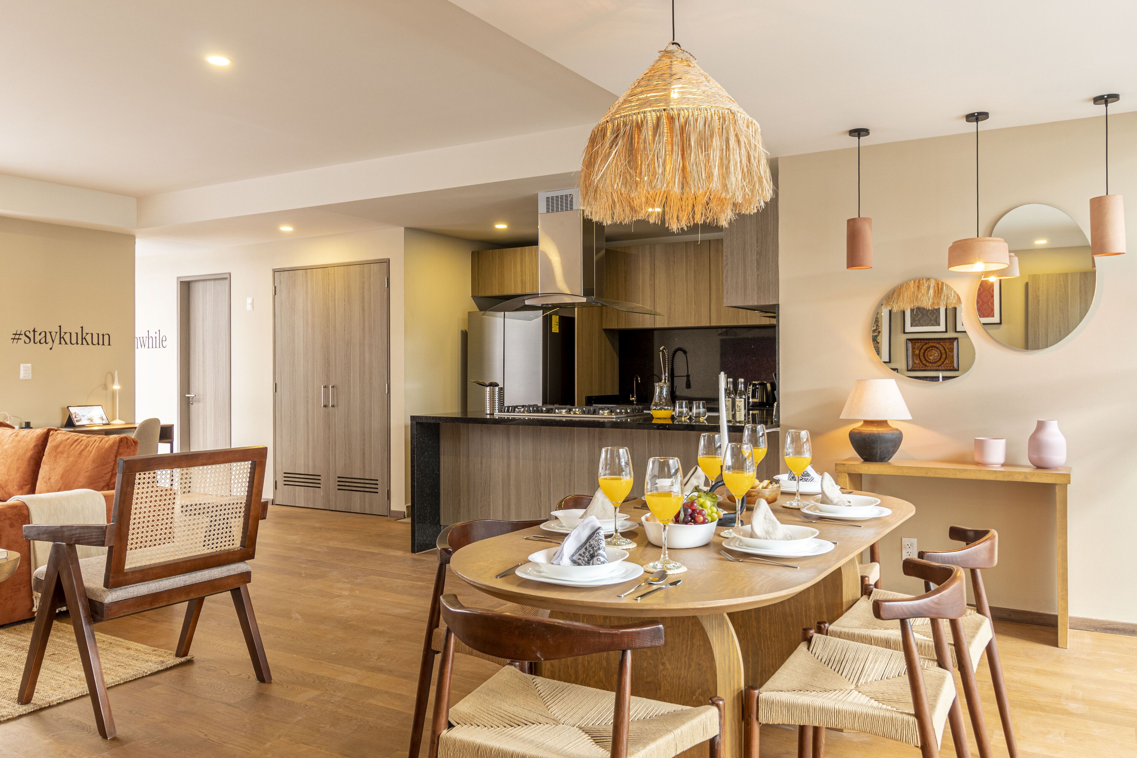 Una cocina moderna con comedor, armarios de madera y una isla central con un espejo redondo.