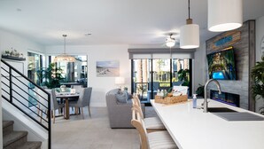 Una cocina moderna con una isla grande, un área de comedor con vistas y una escalera que sube a otro nivel.