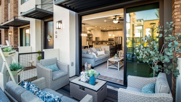 Un apartamento moderno con balcón, amoblado con mobiliario de mimbre y una mesita de centro.