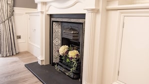Una chimenea con un marco decorativo, una repisa blanca y un hogar negro.