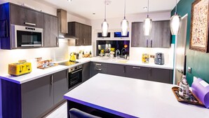 Una cocina moderna con armarios oscuros, un microondas, una estufa y lámparas colgantes.
