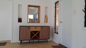 Ein Flur mit einem Holzschrank, einem Spiegel und einer Tür.