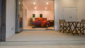 Ein Schlafzimmer mit einem Bett, einem Schreibtisch und einem Stuhl. Eine Tür führt in einen weiteren Raum.
