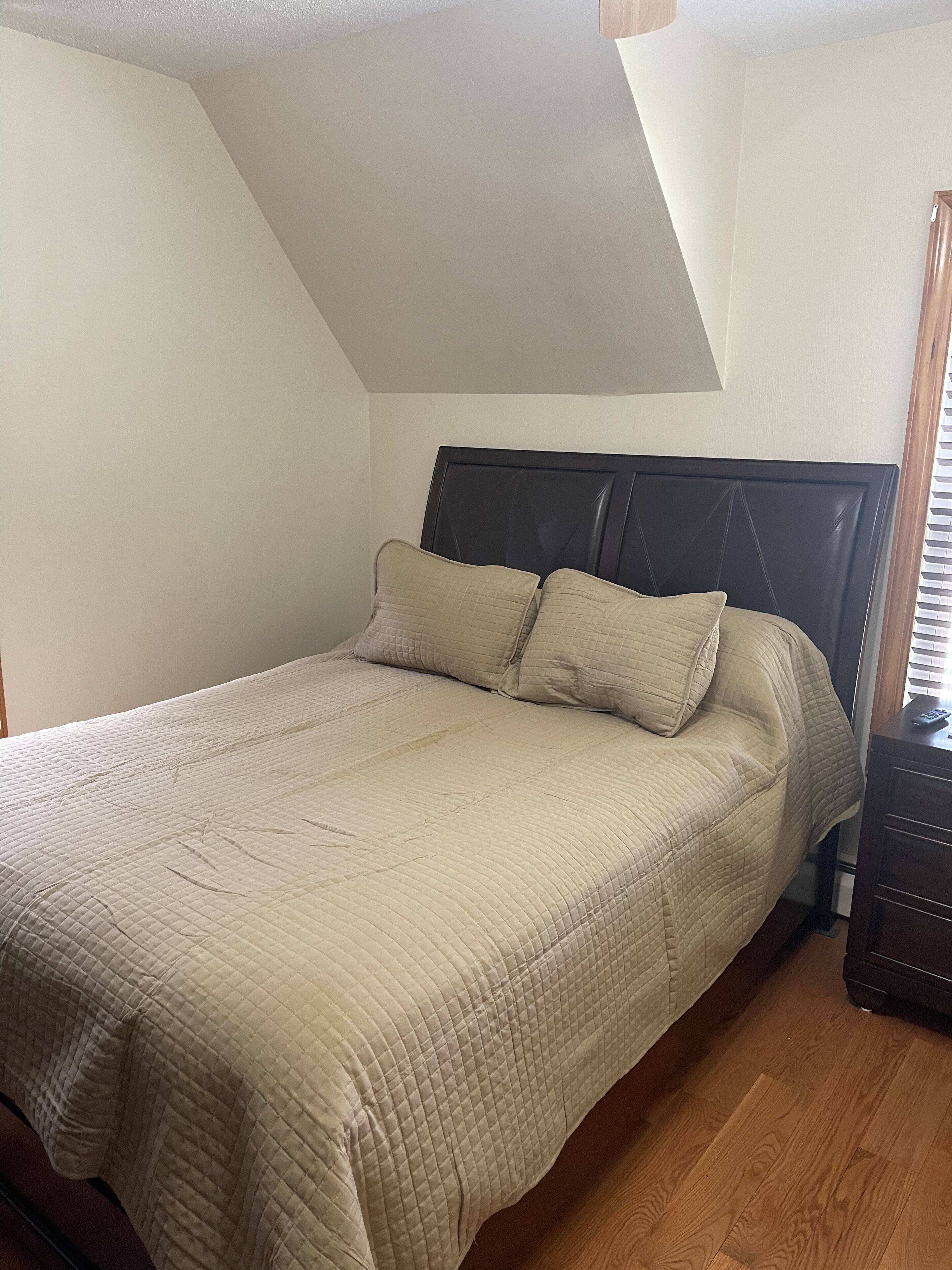Una camera da letto con un letto, una testiera e un comodino.