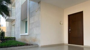 Entrada de um edifício moderno e limpo, com piso de azulejos, uma grande porta de madeira e uma pequena janela.