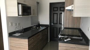 Cozinha moderna com armários de madeira, bancada preta, micro-ondas e fogão.