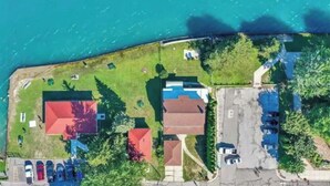 An aerial view of a coastal property with multiple buildings, a parking area, and a body of water.