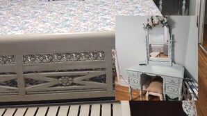 A bedroom with a bed, a nightstand, a dresser, and a mirror.