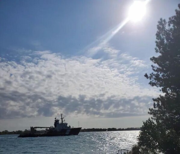 Un barco sobre aguas tranquilas, cielo despejado y nubes.