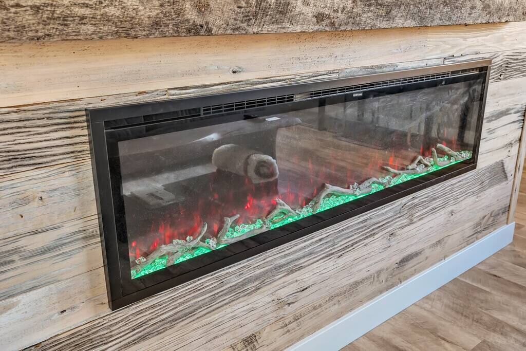 A modern fireplace with a glass front, set against a wooden wall.