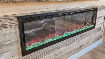 A modern fireplace with a glass front, set against a wooden wall.