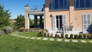 Una casa de dos plantas con balcón, un arco de piedra y un césped bien cuidado.