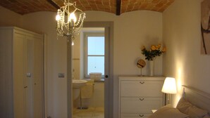 Un dormitorio con cama, cómoda, mesita de noche, lámpara, espejo y candelabro.