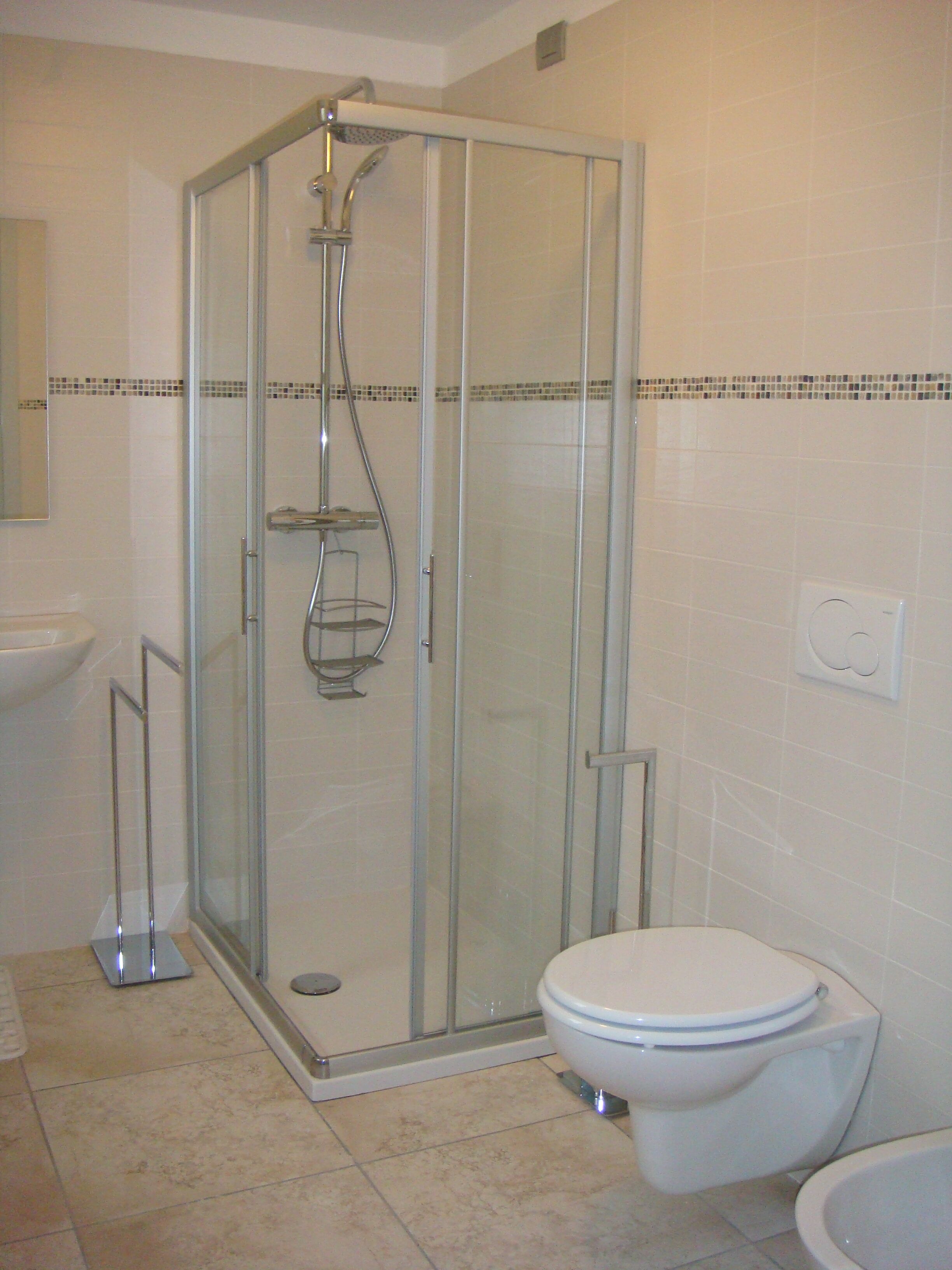 Une salle de bain avec une douche à parois de verre, des toilettes et un lavabo.