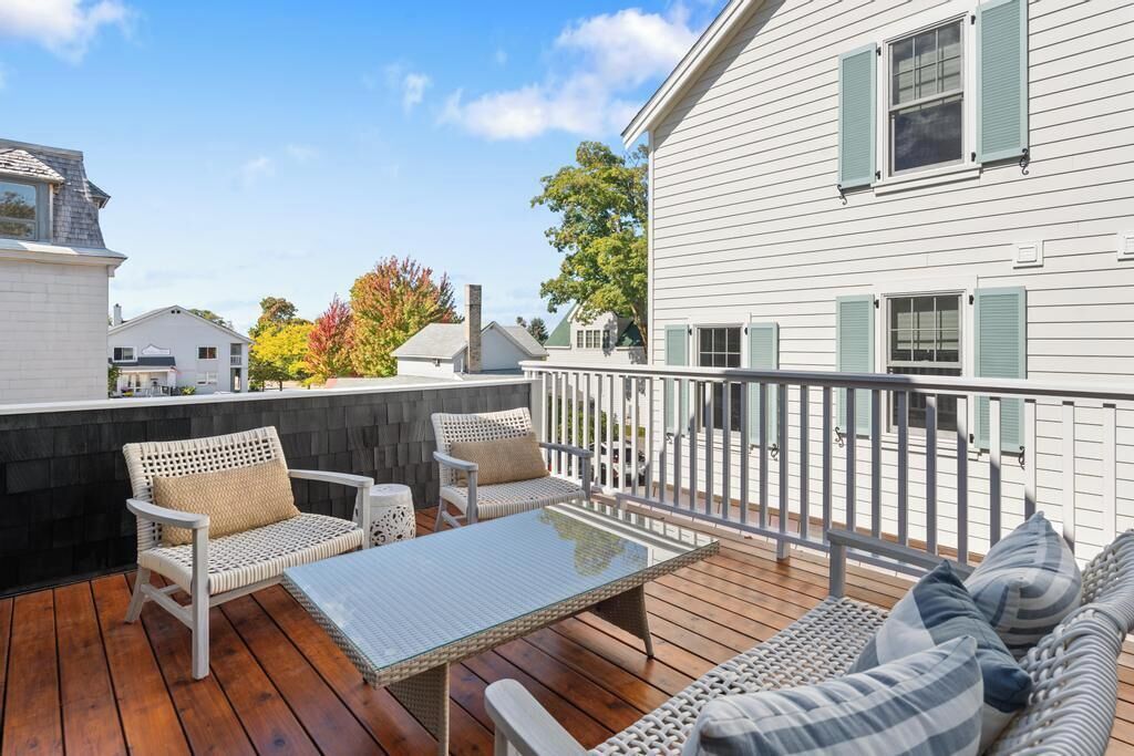 A wooden deck with outdoor furniture, including a table and chairs, and a sofa.