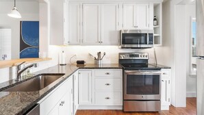 A modern kitchen with white cabinets, stainless steel appliances, and a granite countertop. - Downtown 2nd Floor Apartment with Dramatic Lake Views.   (Petoskey)