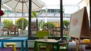 Un espace de jeux pour enfants avec des tables, des chaises et un chevalet sur lequel est dessiné un cœur.