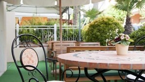 Une terrasse extérieure avec une table ronde, des chaises en métal et une plante en pot.