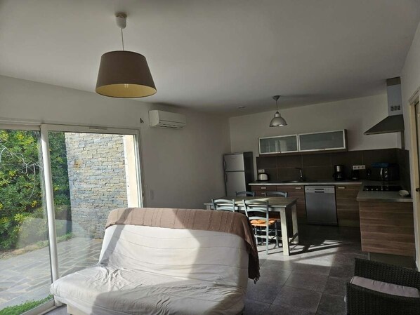Un dormitorio moderno con una cama grande, una zona de comedor y una cocina.
