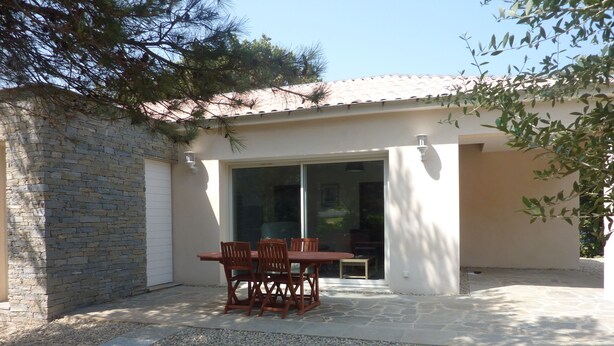 A patio with a table and chairs, a stone wall, and a building with a tiled roof. - Mini villa T3 by the sea at Marine de Sisco, Cap Corse (SISCO)