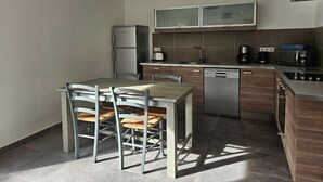 A compact kitchen with a dining table, chairs, a refrigerator, a coffee maker, and a dishwasher. - Mini villa T3 by the sea at Marine de Sisco, Cap Corse (SISCO)