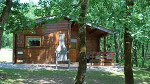 Una cabaña de madera con chimenea, rodeada de árboles.