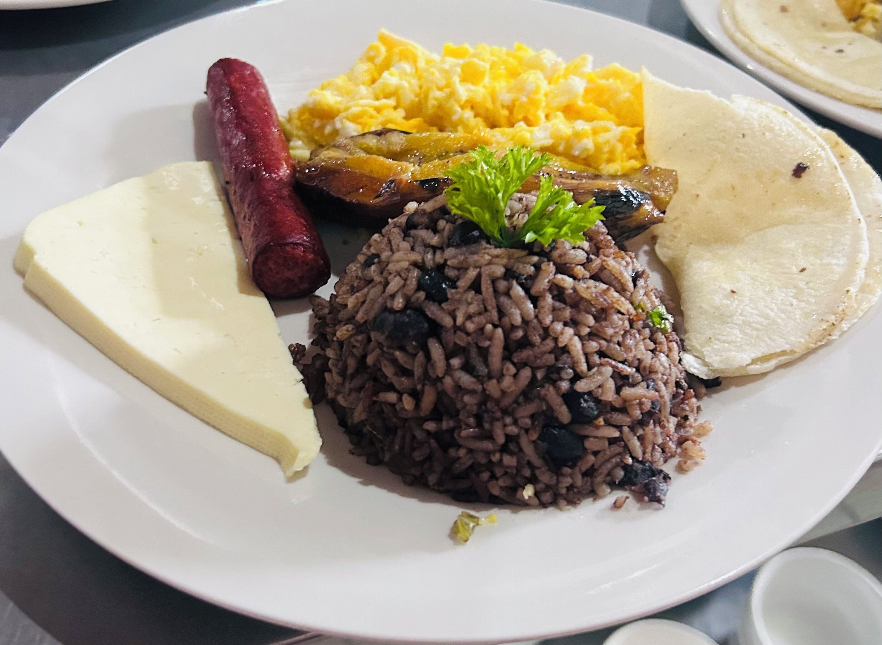 A plate with rice, sausage, scrambled eggs, and a piece of cheese.