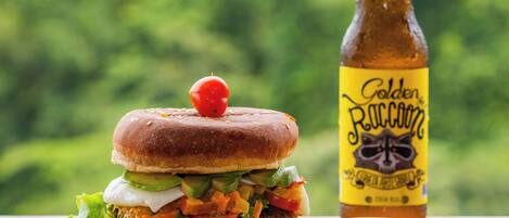 A burger with fries and a bottle of beer on a table with a green background.