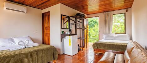 A room with two beds, a wooden ceiling, a refrigerator, and a view of greenery outside.