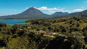 Un paisaje montañoso con un volcán destacado, un lago y edificios dispersos.