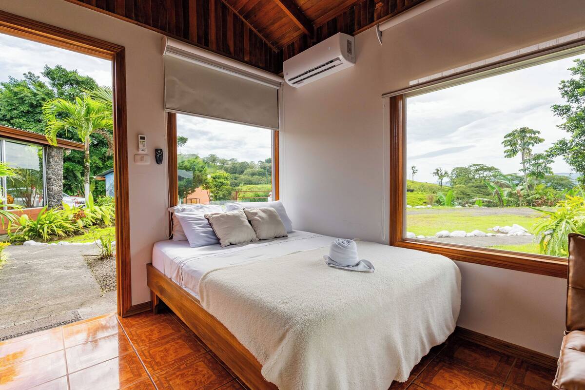 A bedroom with a bed, a window, and an air conditioning unit.
