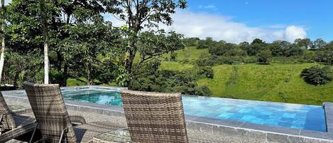 Una piscina al aire libre, sombrillas, sillones reclinables de piscina