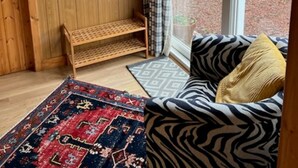 A cozy room with a wooden wall, a bench, a zebra-patterned sofa, and a patterned rug. - Stable Cottage -  spacious one level cottage with private courtyard. (Berwick-upon-Tweed)