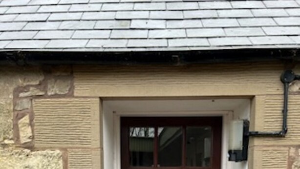 A stone building with a wooden door and a small porch. - Stable Cottage -  spacious one level cottage with private courtyard. (Berwick-upon-Tweed)