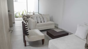 A modern living room with a sofa, a coffee table, and a dining area with chairs.