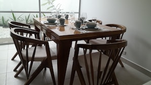 A dining table set with plates, bowls, and glasses, surrounded by wooden chairs.