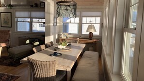 Amplia sala de estar con una gran mesa de comedor de madera, muebles de mimbre y una lámpara colgante.