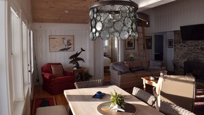 Una sala de estar acogedora con techo de madera, chimenea de piedra y un gran candelabro.