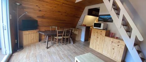 A cozy wooden interior with a dining area, a small table, and a staircase.