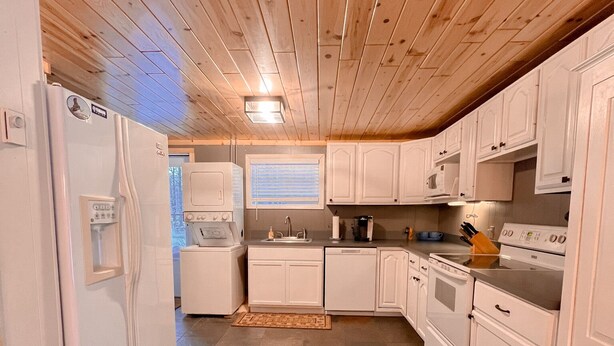 A kitchen with white cabinets, a refrigerator, a microwave, a stove, and a sink.