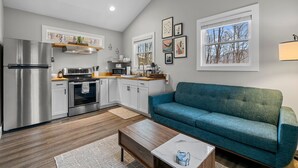 A modern kitchen with stainless steel appliances, a teal sofa, and artwork on the walls.