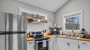 A modern kitchen with stainless steel appliances, white cabinetry, and a wooden countertop.