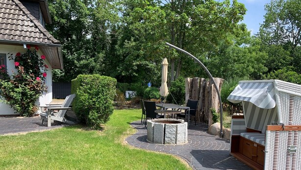 A patio area with a fire pit, outdoor furniture, and a covered seating area. - Bright apartment with direct access to the garden (Sankt Peter-Ording)