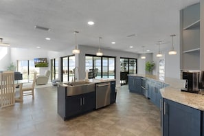 A modern kitchen with a large island, built-in appliances, and ample natural light from large windows.