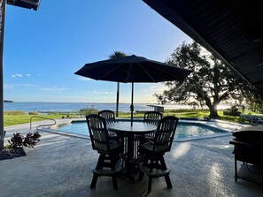 A patio with a pool, outdoor seating, and a view of the ocean.
